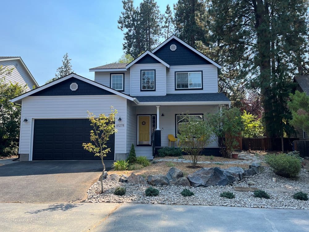 Modern two-story house with black accents, garage, and landscaped front yard.