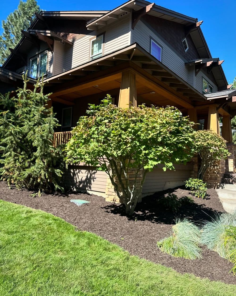 Modern home with a porch, surrounded by landscaped gardens and lush greenery.
